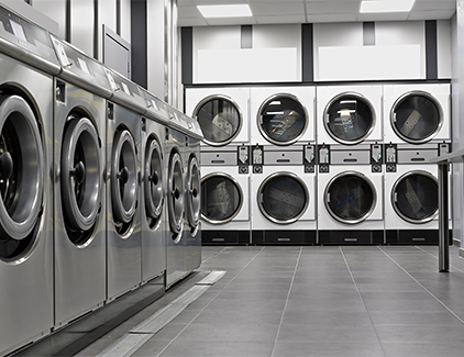 Modern Laundromat, focused on a wall of washer and dryers, representing a high-demand venue for on-site ATMs